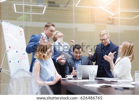 Happy successful business team giving a high fives gesture as they laugh and cheer their success. Signing an important contract, start up concept