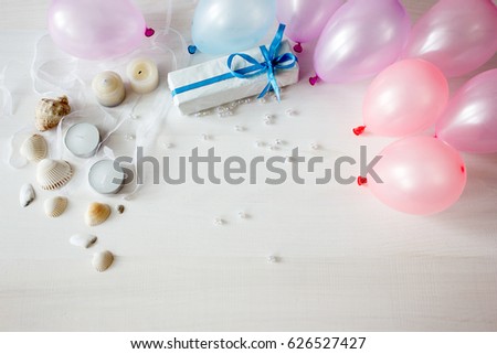 Colorful party frame of balloons, sea shells, gift and candles on a rustic white wood table with central copy space for your greeting , invitation or advertising. Happy birthday concept.