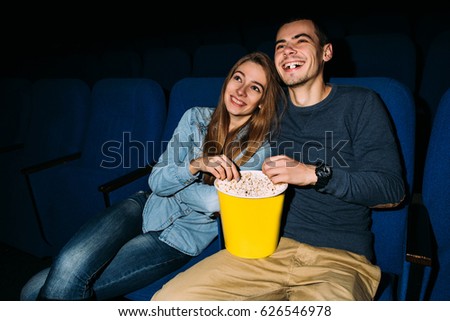 Cinema day. Young happy couple watching funny movie in cinema at their romantic date. World cinema day