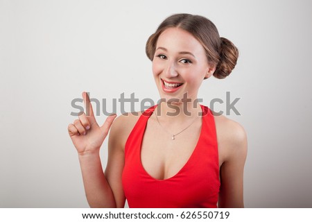 Portrait of a smiling girl pointing finger up at copy space isolated on a white background.