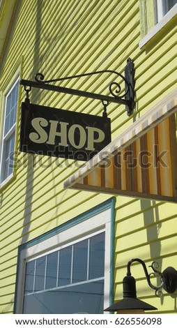 Antique wrought iron bracket with hanging shop sign in front of a building in a small tourist town