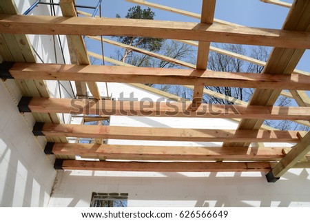 Installation of wooden beams at construction the roof truss system of the house.