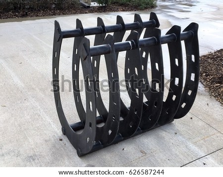 Beautiful Wrought Iron Horseshoe shaped bike stand, very unique, black with holes on concrete.