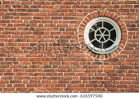 Round and vintage wooden window on brick wall. White window on red brick wall. Background of old red vintage brick wall and window. Abstract orange-red brick wall pattern. Filled full frame picture.