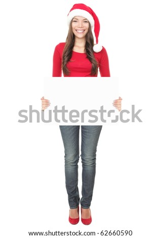 Christmas woman holding empty paper sign standing in Santa hat. Mixed Asian / Caucasian young woman model isolated in full length on white background.