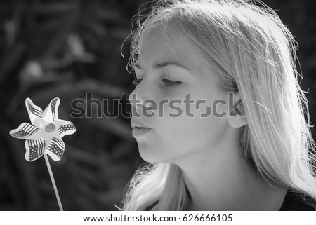 Young girl blows pinwheel in yard in black and white