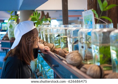 A young woman travelerÂ watching a Fighting Fish in Bottles  at Siamese Fighting Fish Gallery ,Thailand