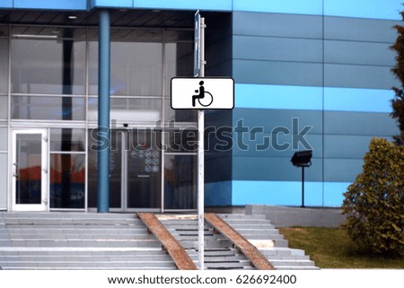 a parking place for disabled people equipped with indicative car signs parked near a public building
