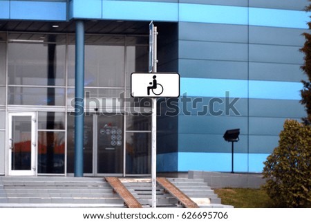 a parking place for disabled people equipped with indicative car signs parked near a public building