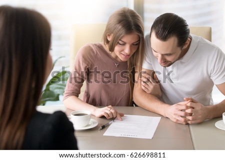 Smiling family couple reading contractual terms before signing contract, examining documents to make decision about mortgage, considering investment in property, calculating total loan liabilities 