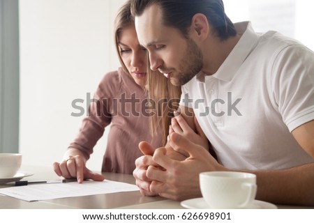 Serious couple studying contract agreement, reading terms and conditions attentively before signing, husband and wife calculating domestic bills, considering mortgage loan offer, health insurance 