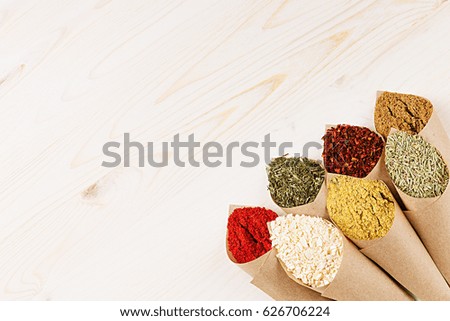 Asian colorful powder spices in rustic paper corner on white wooden board with copy space.