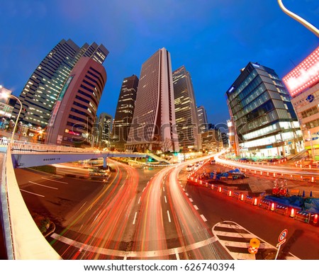 Beautiful scenery of Tokyo Downtown at rush hour, with view of traffic light trails on busy streets and modern high rise office towers under blue twilight in background in Shinjuku, Tokyo, Japan