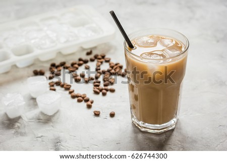 coffee break with cold iced latte and beans on stone table background