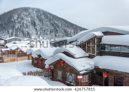 Wooden houses covered in snow in the Snow Village in Heilongjiang Province, northeast of China. The snow hangs down from the roof of the house. Royalty-Free Stock Photo #626757815