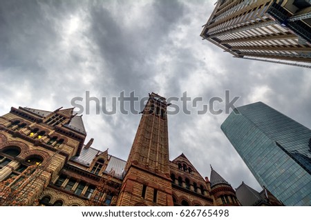 Looking up at old and architectural buildings at grey cloudy skies