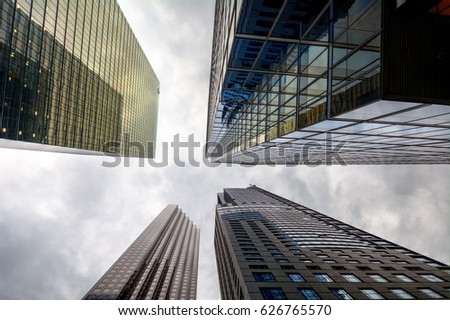 Buildings with interesting windows in a city looking up to the grey skies with clouds