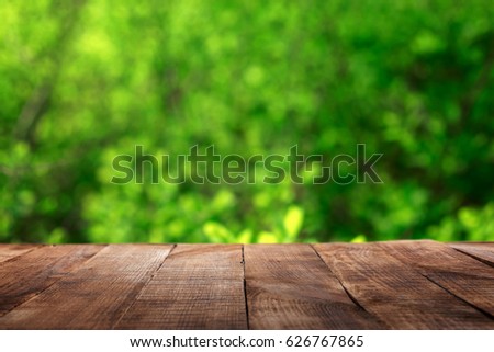 Empty wooden table with blur green leaves bokeh background for product display montage