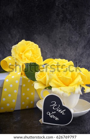 HAppy Mothers Day gift of yellow roses in vintage style china tea cup on black slate background.  