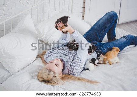 Beautiful girl is kissing puppies. Emotions and feelings. Love to the animals. Little dogs on the bed. 
