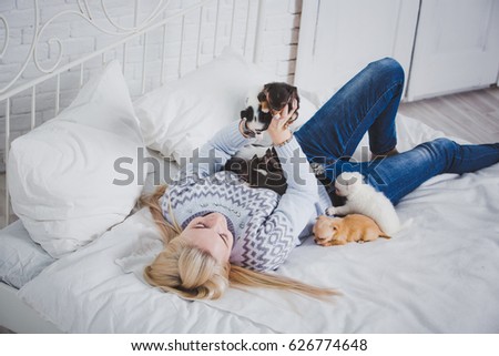 Beautiful girl is kissing puppies. Emotions and feelings. Love to the animals. Little dogs on the bed. 
