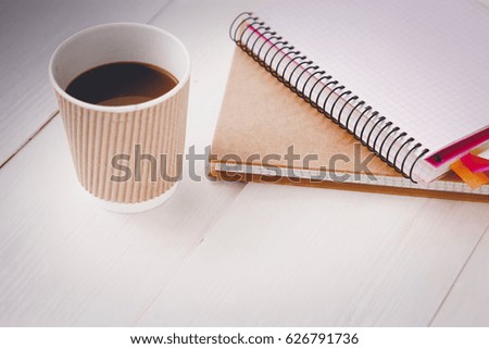 Top view image of open notebook with blank pages next to cup of coffee on wooden table