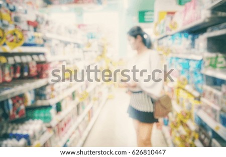 Blurred photo of housewife choosing goods in supermarket store 