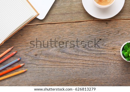 Top view image of open notebook with blank pages next to cup of coffee on wooden table