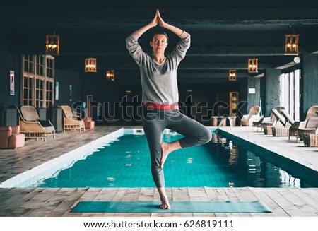 Young beautiful woman practices yoga at the swimming pool. Wellness concept. Sport and yoga, woman happiness. Toned picture