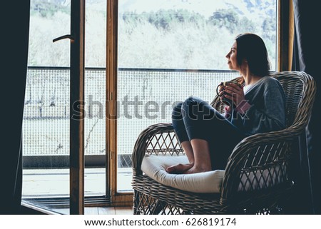 Young beautiful woman enjoys her morning tea in the armchair looking at the mountain view. Freedom concept. Calmness and relax, woman happiness. Toned picture