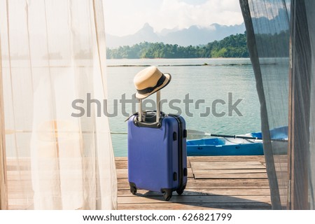 Time to Relax, traveling suitcase with hat standing on the floor out the room, travel lifestyle concept. Royalty-Free Stock Photo #626821799