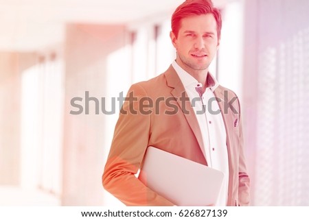 Portrait of young businessman holding laptop in new office