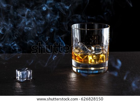 whiskey with ice in glass on dark background
