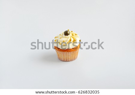 Cupcake with white cream, blueberry and gold confectionery sprinkling. Isolated. Picture for a menu or a confectionery catalog.