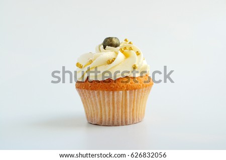 Cupcake with white cream, blueberry and gold confectionery sprinkling. Picture for a menu or a confectionery catalog.