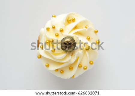 Cupcake with white cream, blueberry and gold confectionery sprinkling. Top view. Picture for a menu or a confectionery catalog.