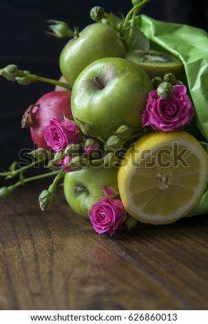 Bouquet of fruits on wooden background. Apples, pomegranate and lemon