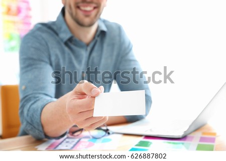 Handsome young designer with business card in office, closeup