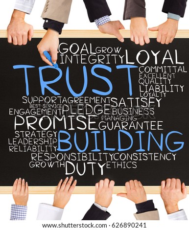 Photo of business hands holding blackboard and writing TRUST BUILDING concept
