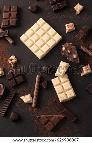 Mix of different kinds of chocolate bars spread all over wooden surface