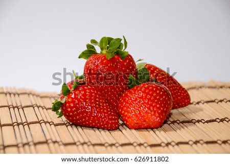 Four delicious fresh strawberries on a wooden surface in the spring in the morning for breakfast and mood