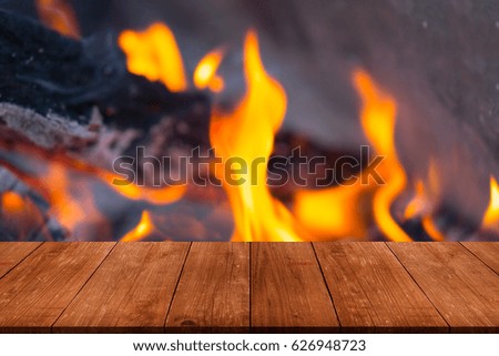 View from wooden table to bright flame of bonfire. Collage. Defocused.