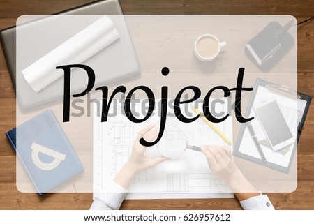 Girl is sitting at table with business accessories, cup of coffee and a laptop, works with drawings, graphs, tables, using smartphone. With text Project.