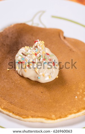 Chocolate cream with colorful sprinkles on the american pancakes.