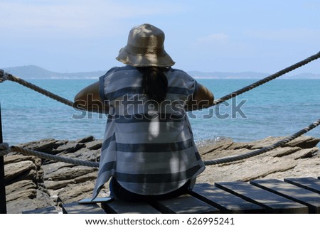 Girl sitting alone on a the wooden bridge on the sea