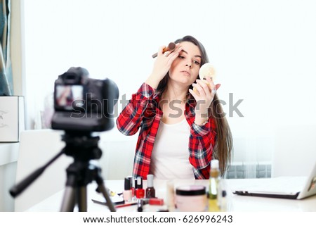 A young girl blogger writes a new edition.Beauty-blog.Girl beauty blogger in front of the camera.Girl with laptop Cydia at the table.Cosmetics on the table