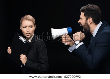 angry businessman with loudspeaker shouting on colleague isolated on black 