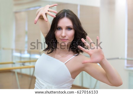 Adult beautiful girl in white dress dancing in a dance class