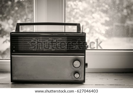 Old stylish portable radio receiver installed on windowsill, monochrome image in vintage style, dark edges, vignetting