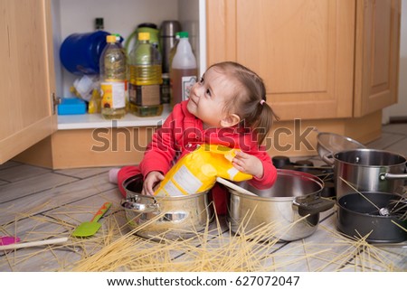 Waggish little girl at kitchen cooking spaghetti